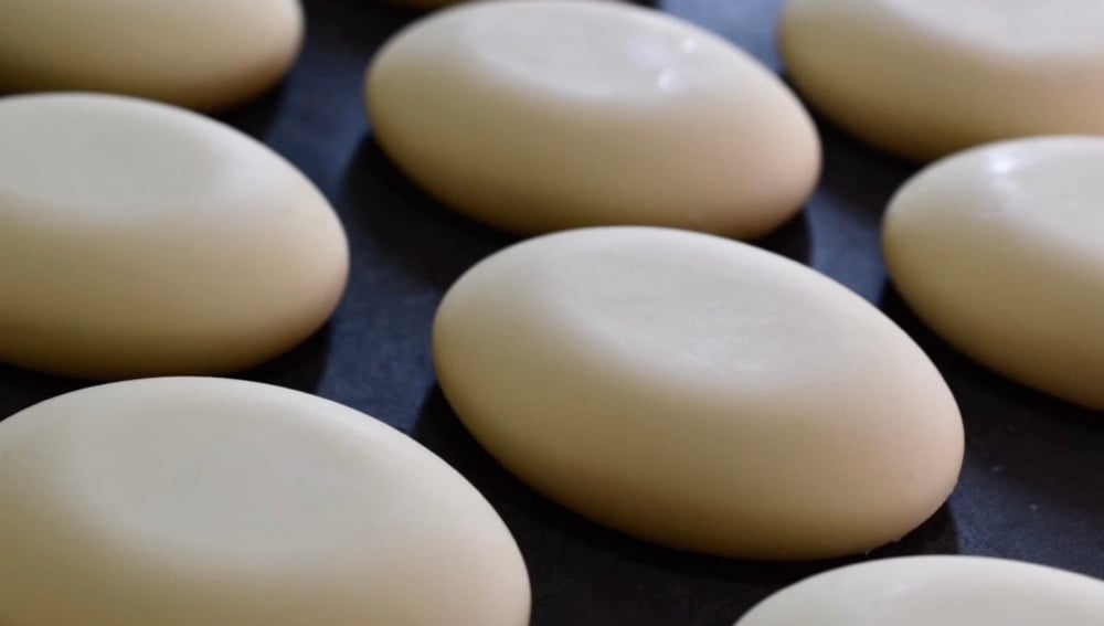 White oval soap bars on a dark wood table