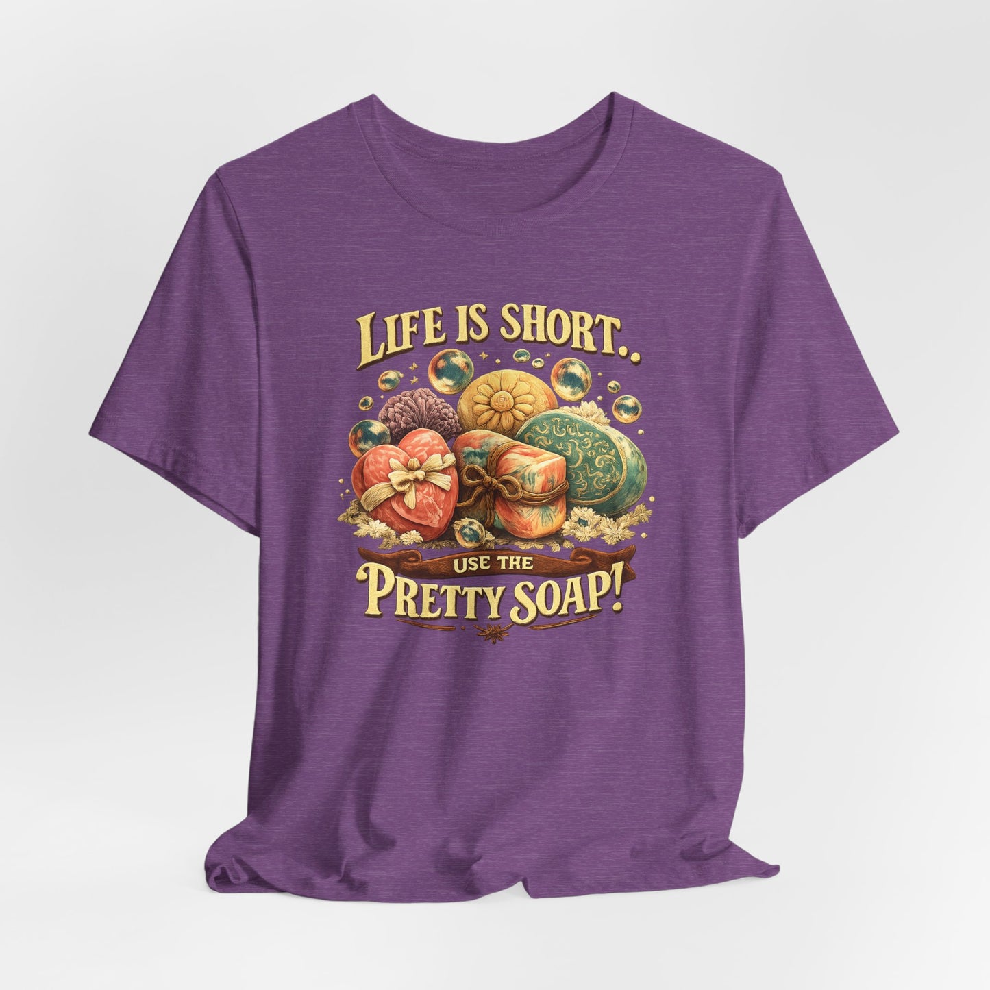 The purple t-shirt displays a graphic of fancy, decorative soaps and bubbles with the text "Life is short...use the pretty soap!".
