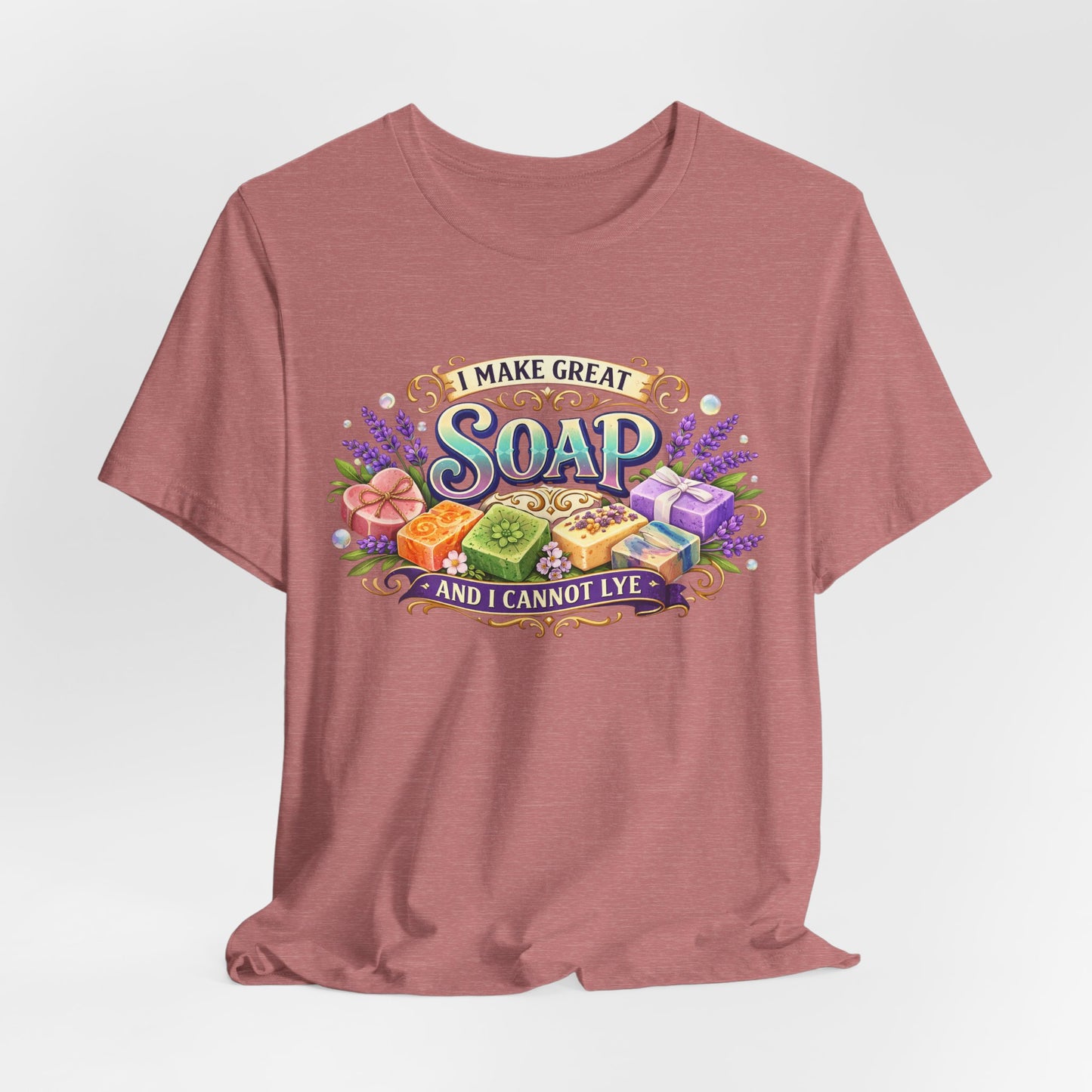 Displaying a mauve t-shirt featuring a whimsical design of colorful artisan soaps and the humorous phrase "I Make Great Soap and I Cannot Lye".

