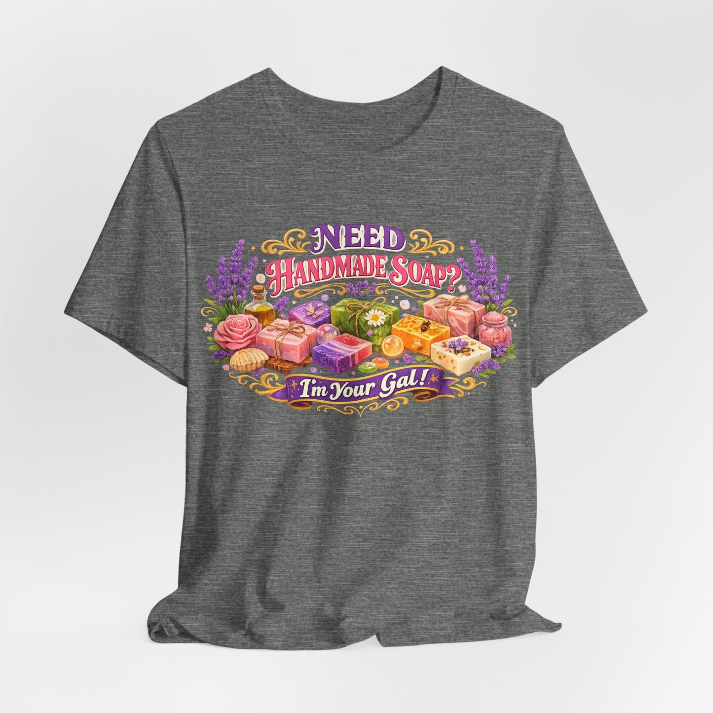 Gray t-shirt displays a colorful design asking "Need Handmade Soap?" surrounded by lavender, roses, and various bars of artisan soap.
