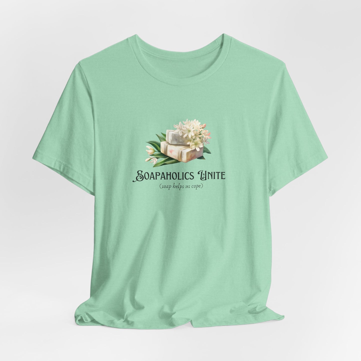 Mint green t-shirt with a graphic design and text that says Soapaholics  unite on a light gray background 