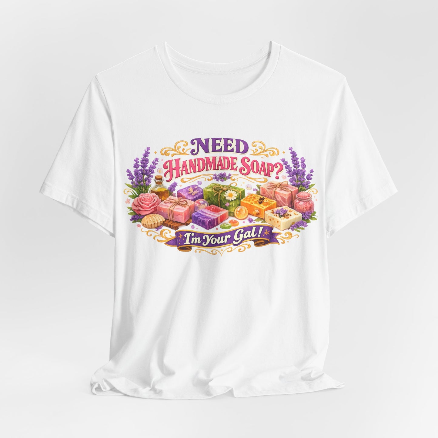 A white t-shirt displays colorful handmade soap designs with lavender and the text "Need Handmade Soap? I'm Your Gal!".
