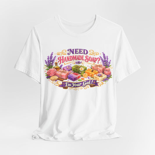 A white t-shirt displays colorful handmade soap designs with lavender and the text "Need Handmade Soap? I'm Your Gal!".
