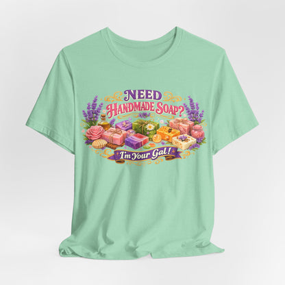 Mint t-shirt features a vibrant design promoting handmade soap with the playful message "Need Handmade Soap? I'm Your Gal!".
