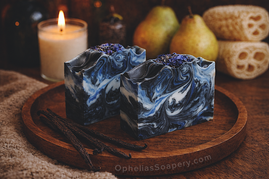 Two marbled blue and white soap bars on a wooden tray with vanilla beans and
A candle in the background.