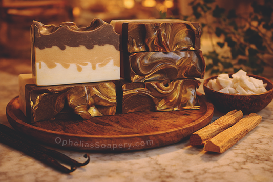 Stack of soap bars with a wooden stand on a marble surface, featuring 'Ophelia's Soapery' branding.