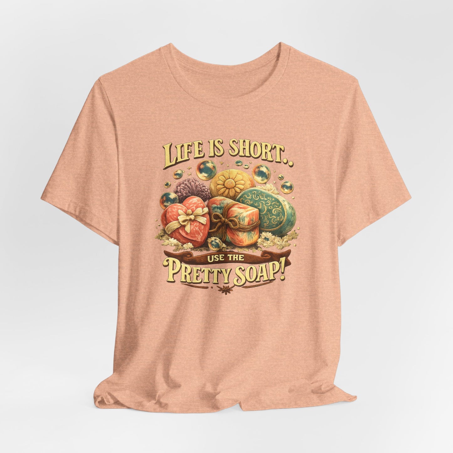 Peach t-shirt displays a graphic with various handmade soaps and the quote, "Life is short, use the pretty soap."
