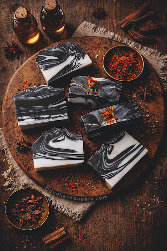 Marble-patterned soaps on a wooden board with star anise and cinnamon, featuring OpheiasSoapery.com branding.