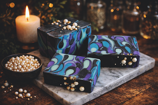 Decorative soap bars with pearl embellishments on a marble slab, candle and glassware in the background.