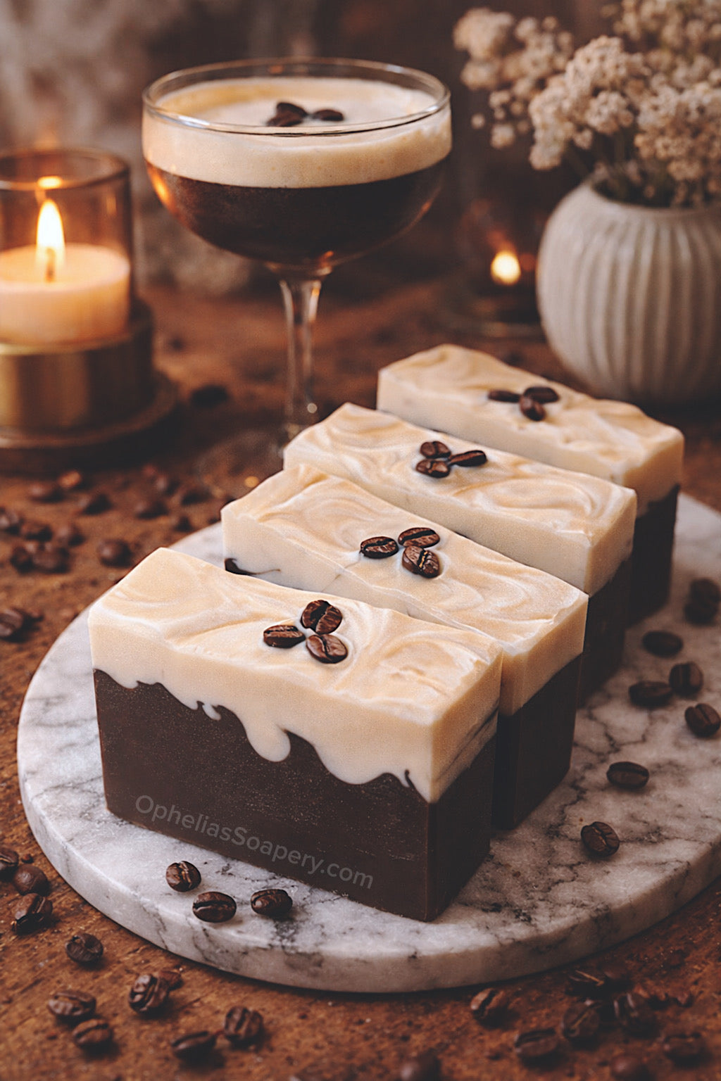 Three coffee-themed soap bars with coffee beans on a marble board, with a glass of coffee and candle in the background.