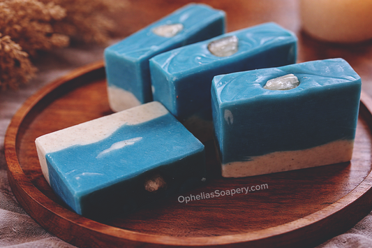Blue and white soap bars on a wooden tray with 'Ophelia's Soapery' branding.