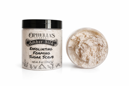 Ophelia's Soapery Amber Silk Exfoliating Foaming Sugar Scrub with a scoop of scrub on a white background
